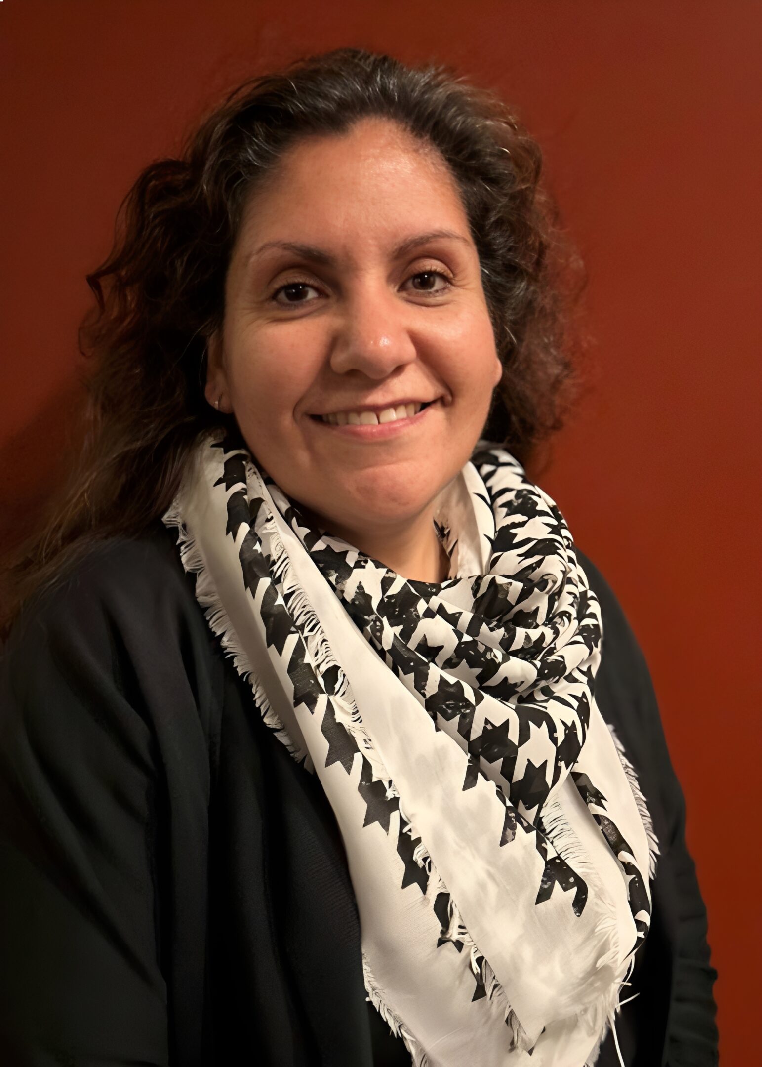 Smiling person wearing a patterned scarf.