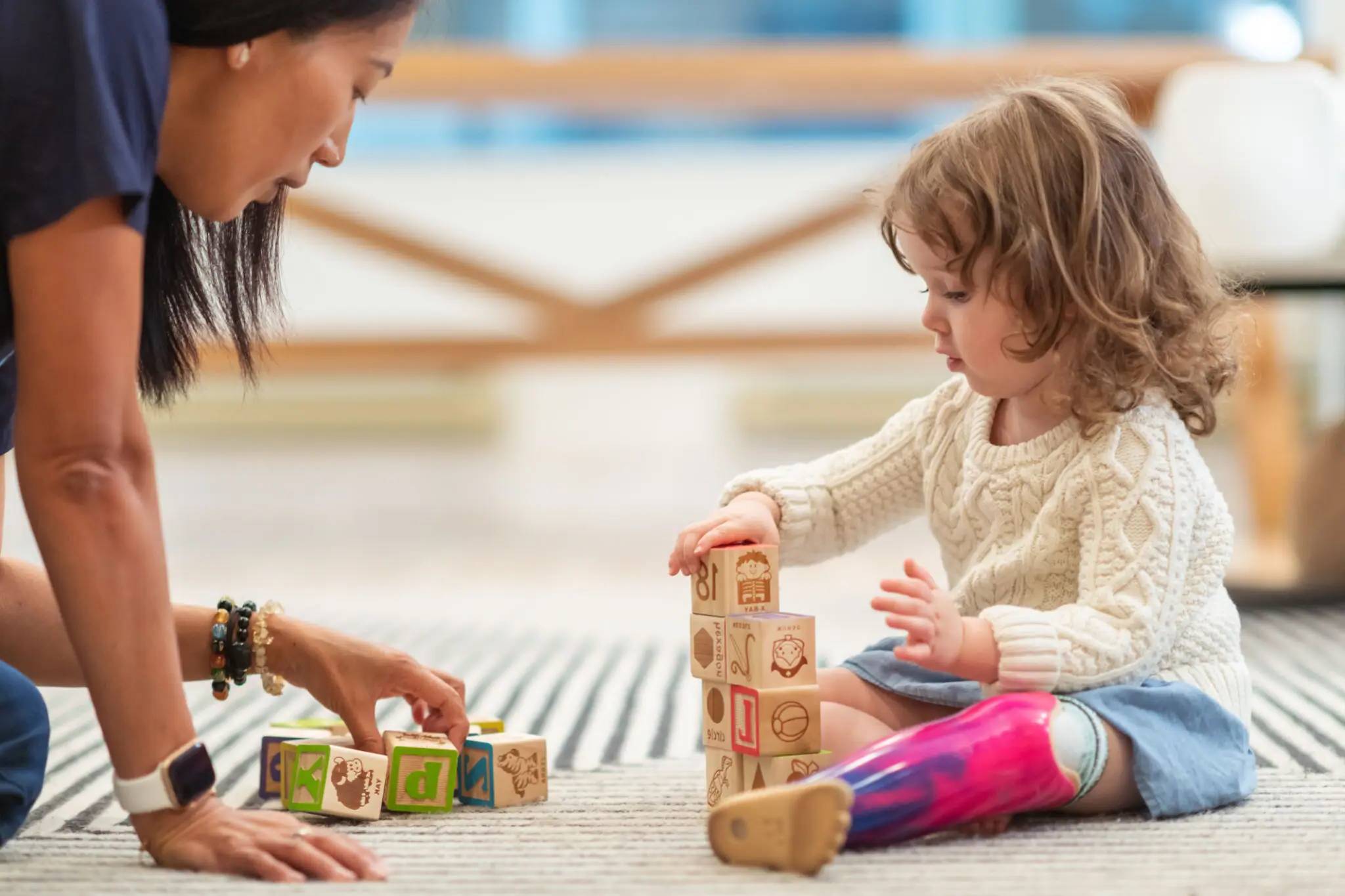 Child stacking blocks with adult assistance.