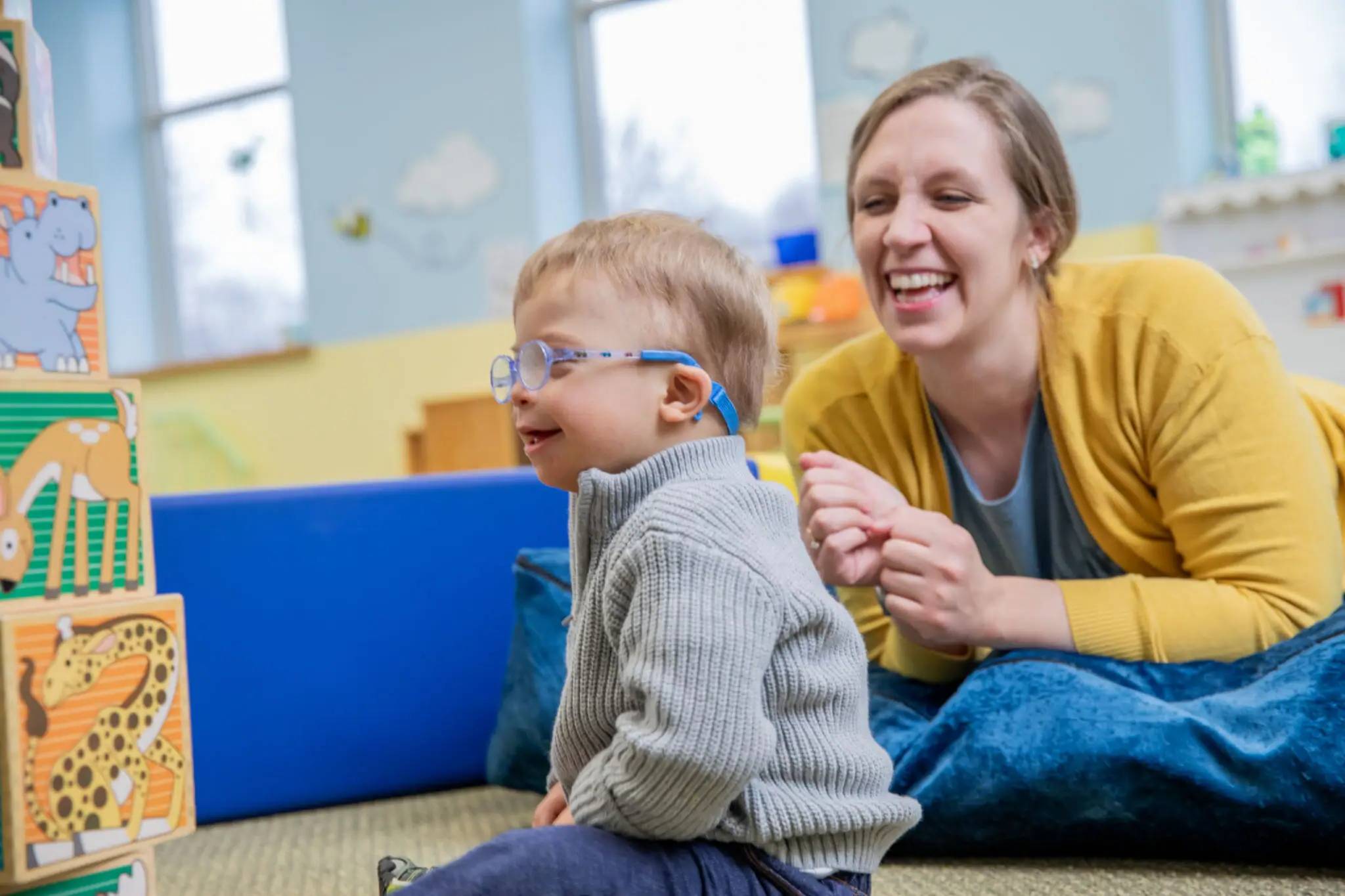 Child and adult playing with toy blocks.