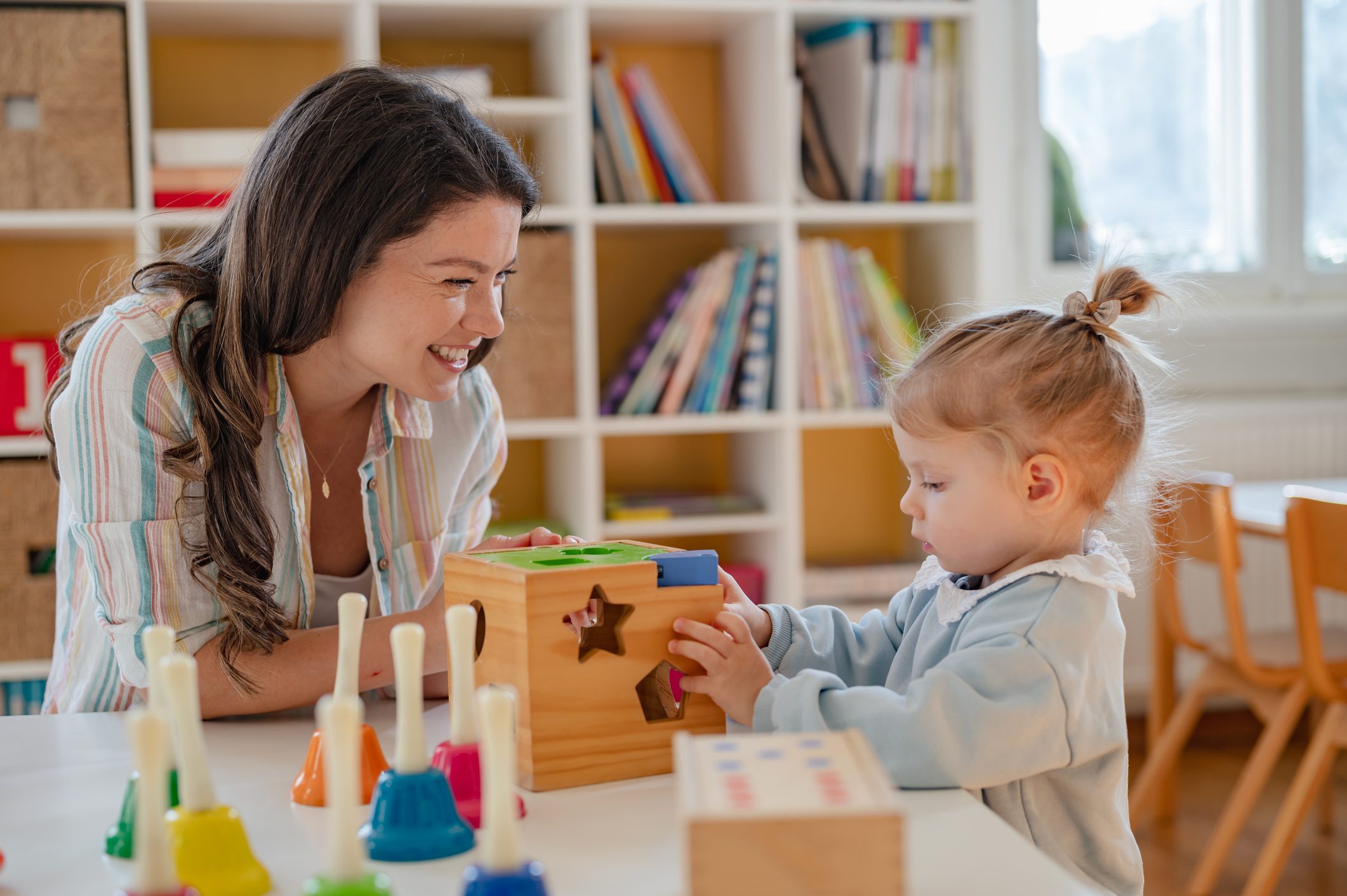 Teacher and child playing with educational toys.
