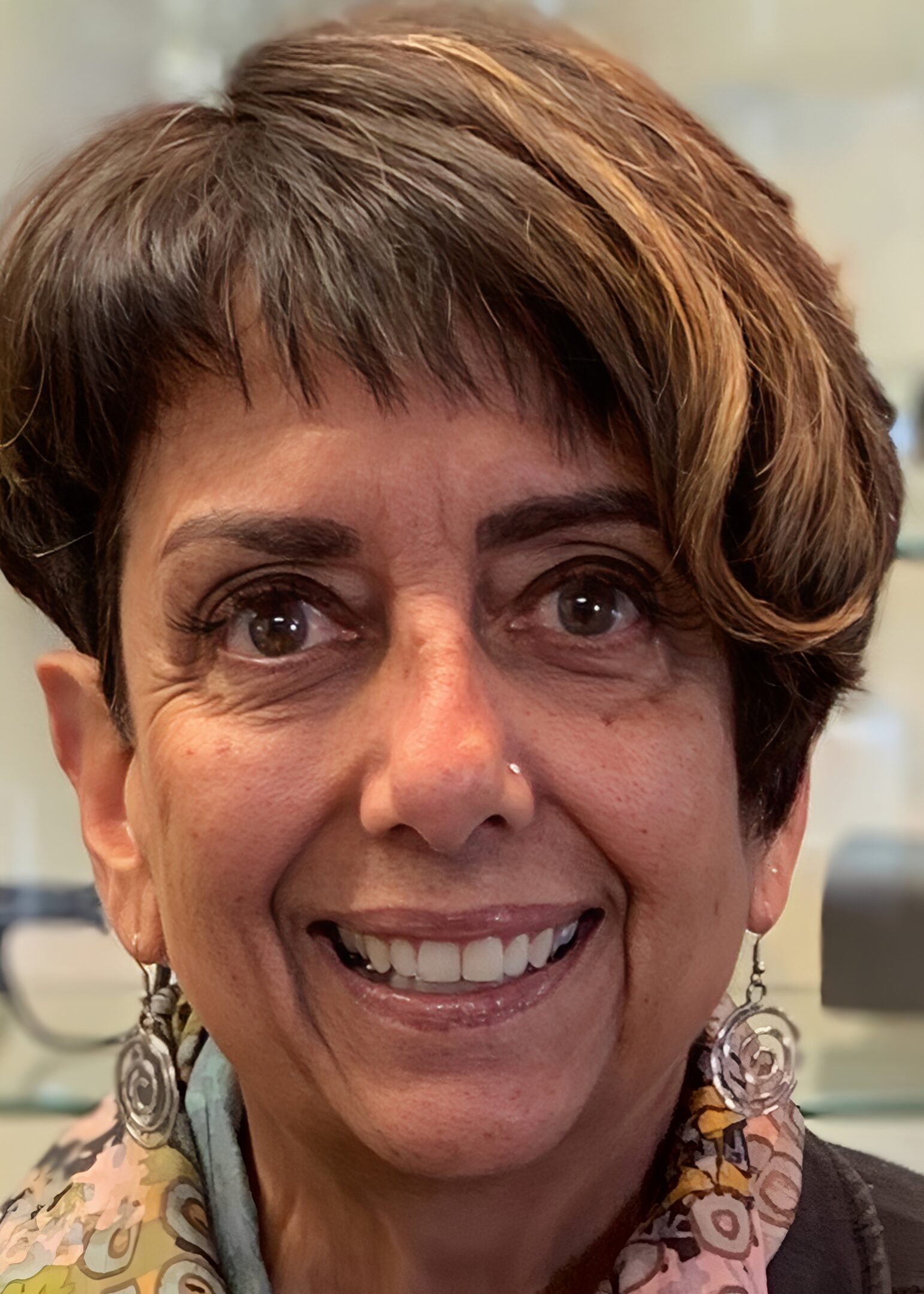 Smiling person with short hair and earrings.